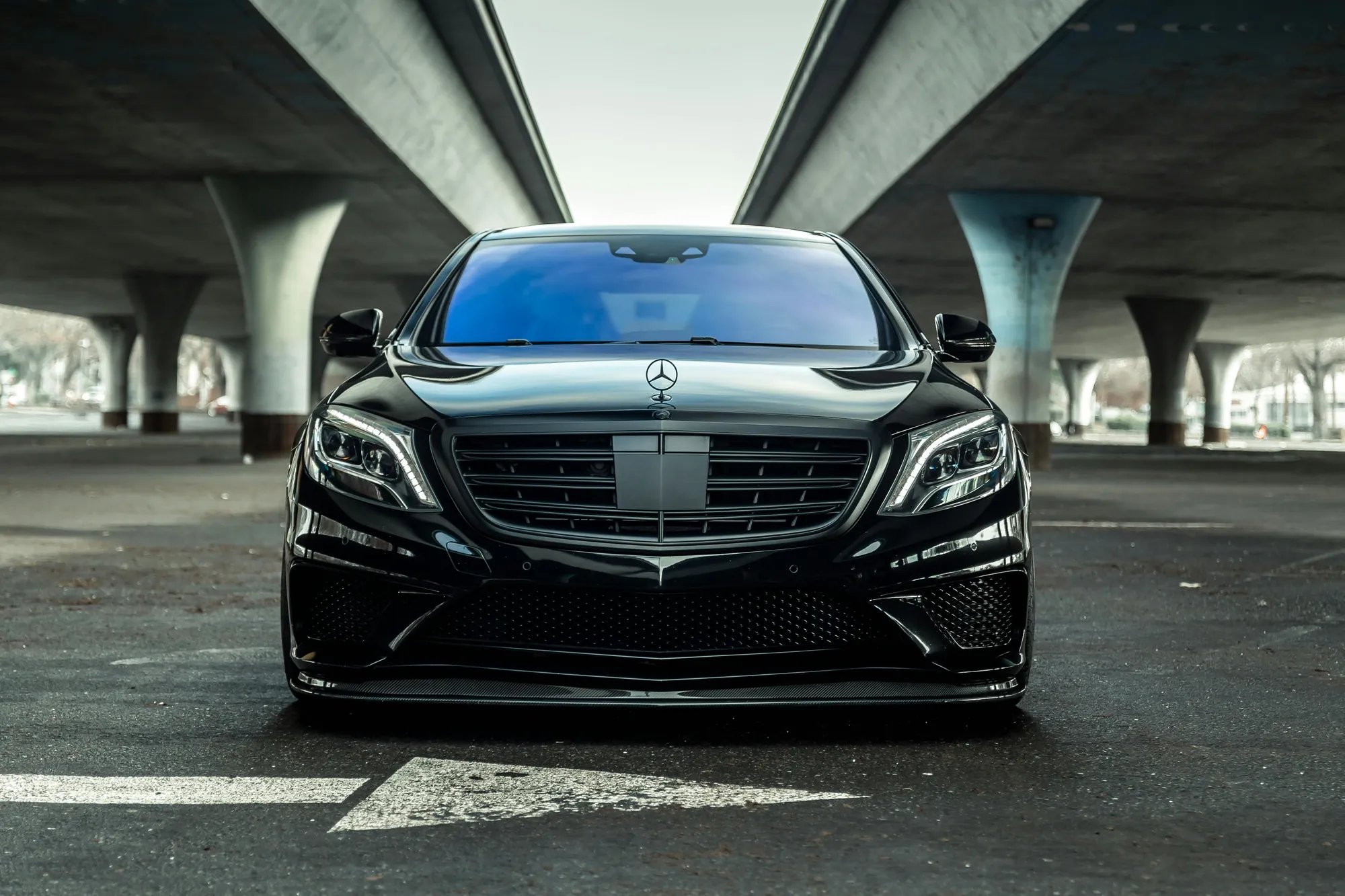 Black Mercedes sedan with a clear, flawless windshield parked under a highway overpass